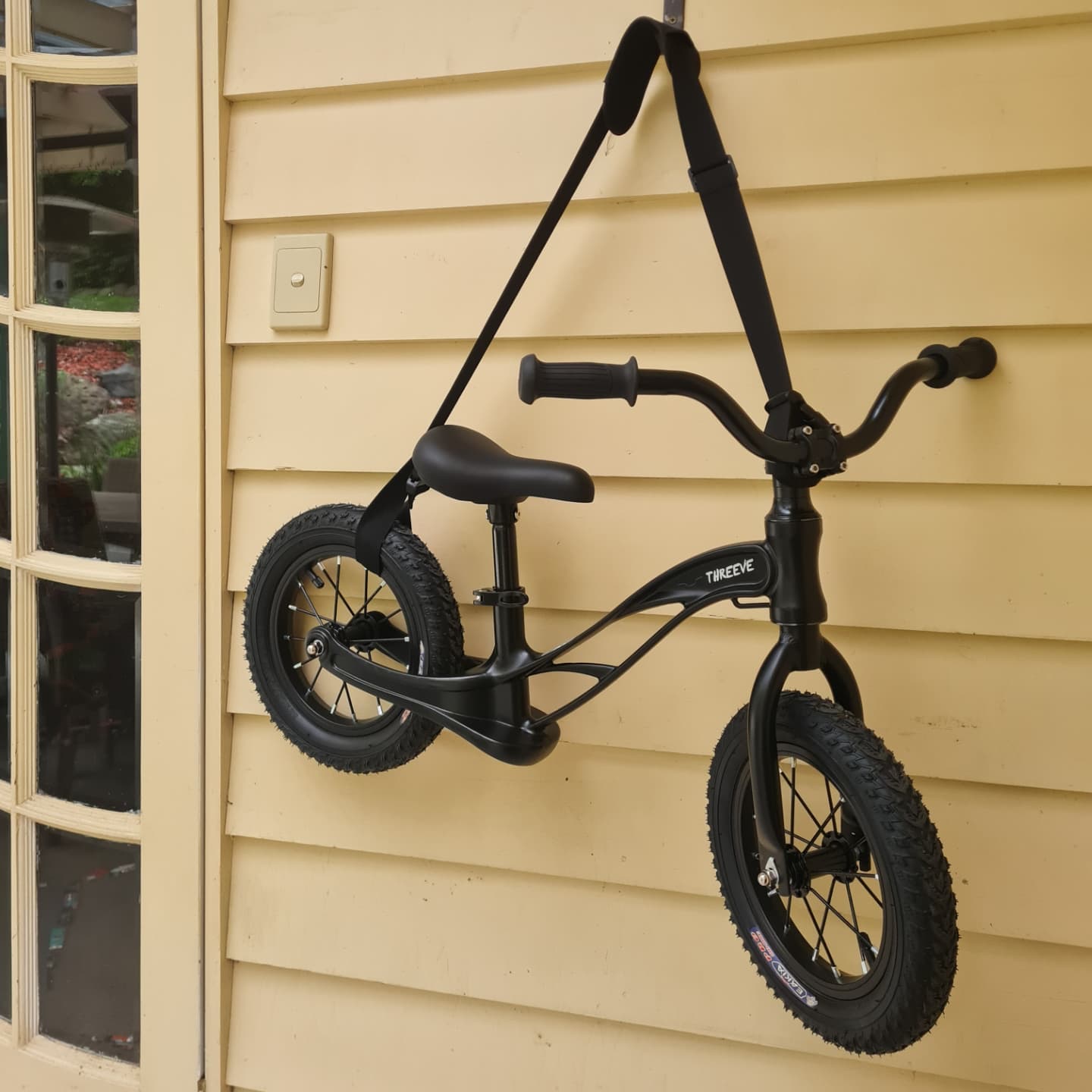 Balance Bike hanging in storage from a carry strap on a hook